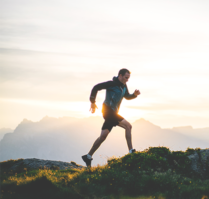 A man runs on a mountain top as part of his men's health routine for fitness.