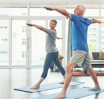 An elderly couple exercising at home. 