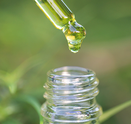 Organic CBD Oil with dropper displayed with a green background.