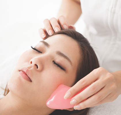 A woman uses the Gua Sha practice to reduce inflammation as part of her skincare routine.